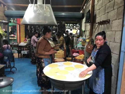 vrouwen met rode warme hoofden in traditionele kleding die verse tortillas staan te bakken midden in de overdekte markthallen op ijzeren platen boven houtvuren